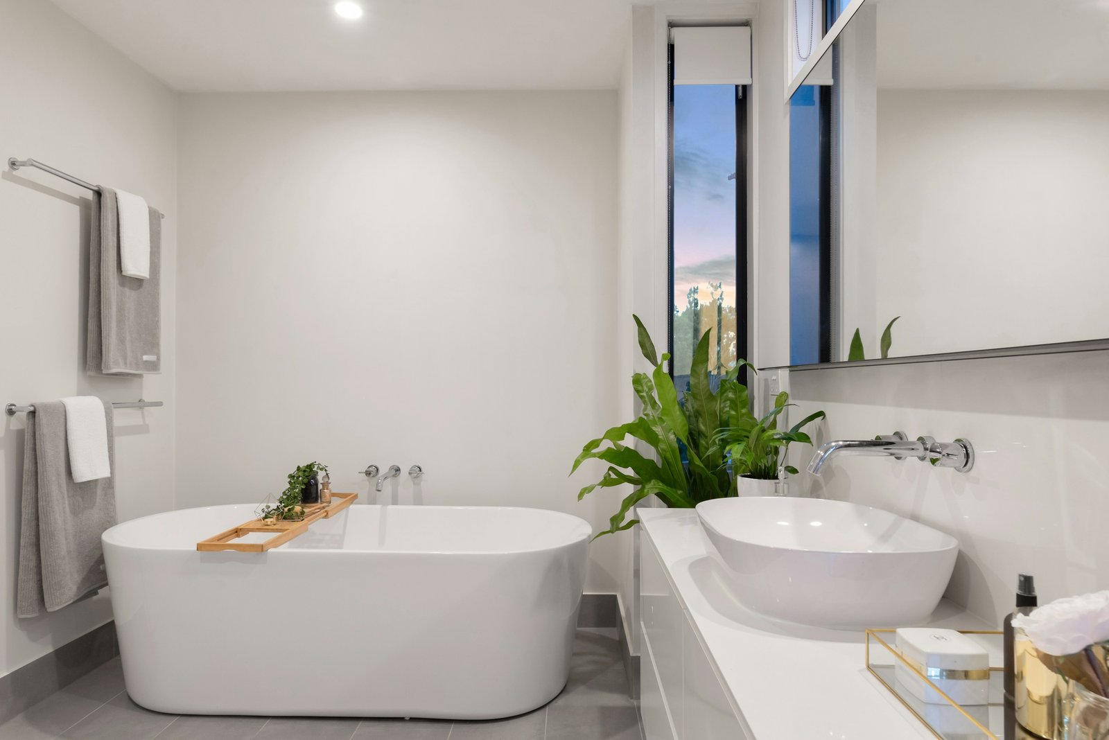 Light bathroom with a freestanding tub and greenery. Stock design inspiration.