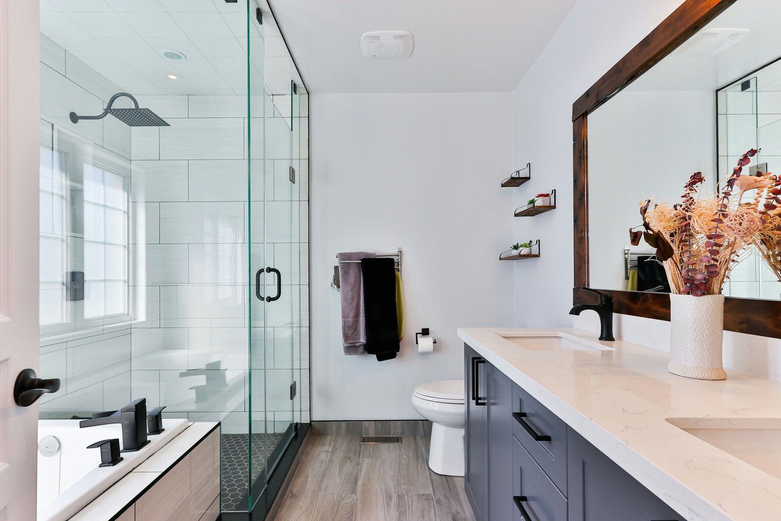 Bathroom with a glass shower, white walls and wood look flooring. Stock design inspiration.